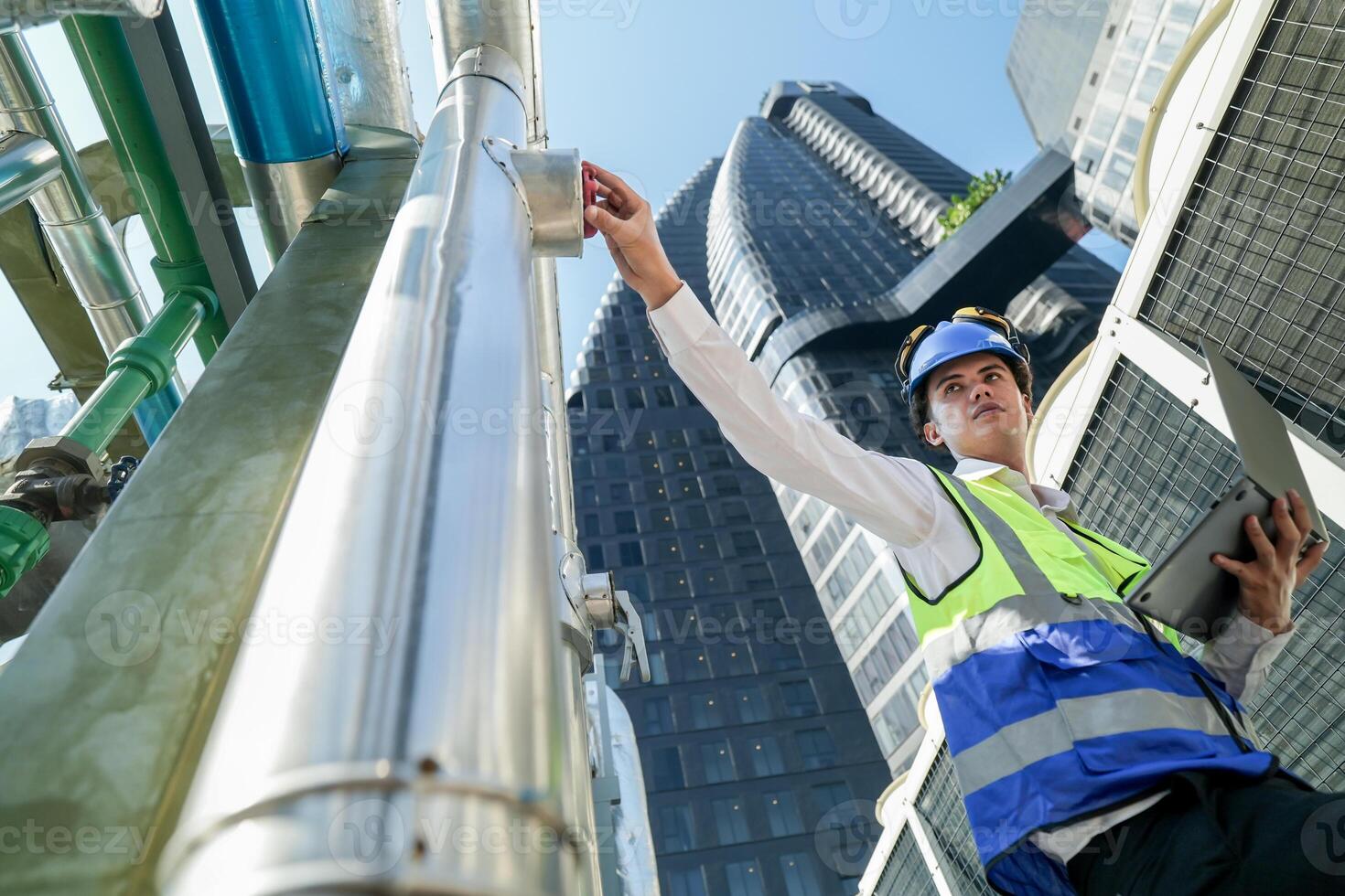 Industrial engineer adjusting pipeline valve with radio communication on construction site. Engineer on urban construction site using radio to coordinate with team on a sunny industrial rooftop. photo