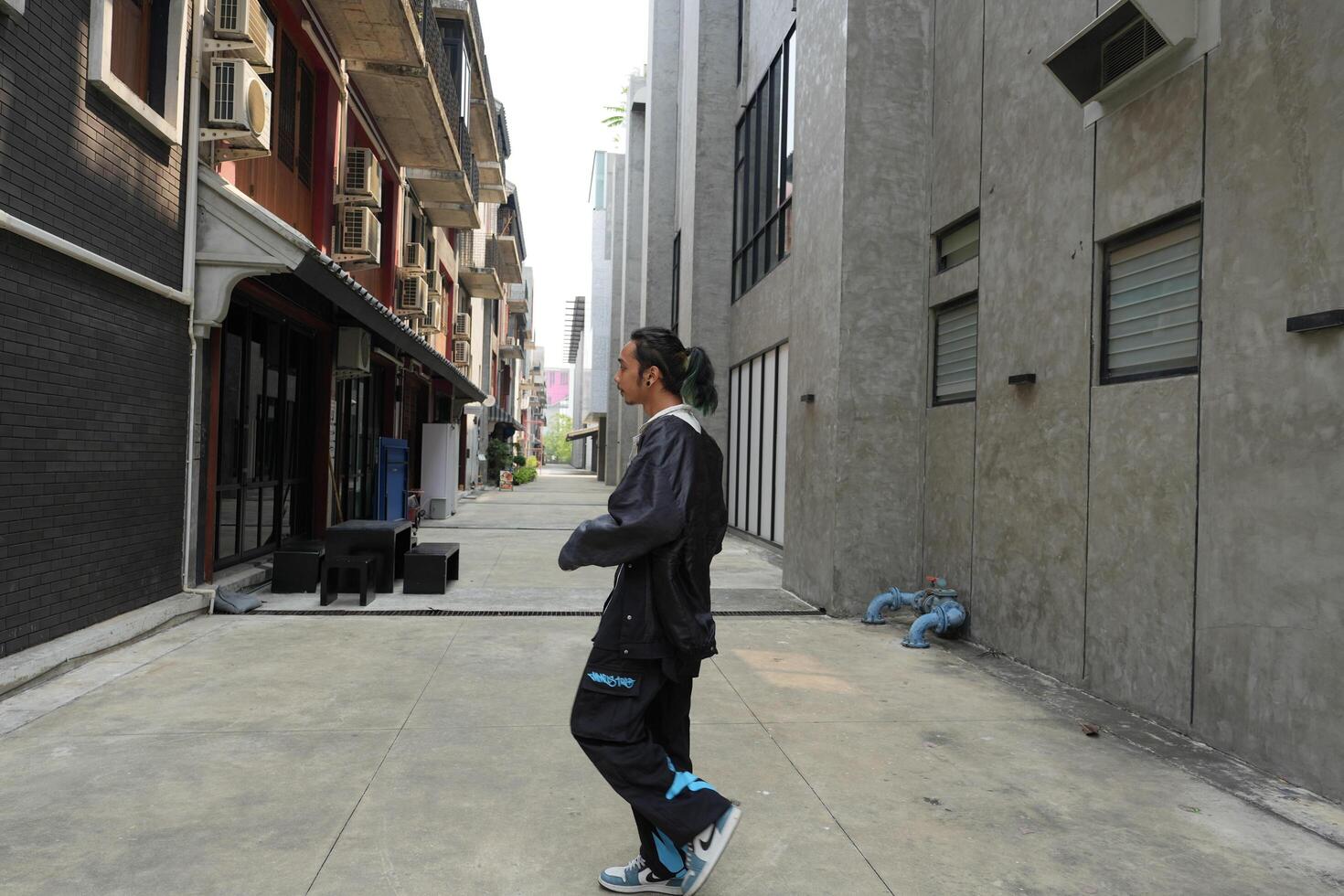 ASian man is dancing in hip hop style at outdoor space. Professional solo dancer is performing in public area. photo