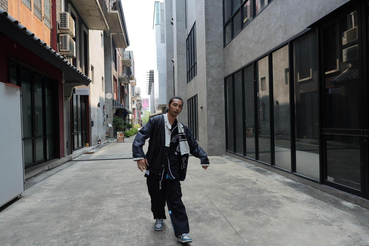 ASian man is dancing in hip hop style at outdoor space. Professional solo dancer is performing in public area. photo