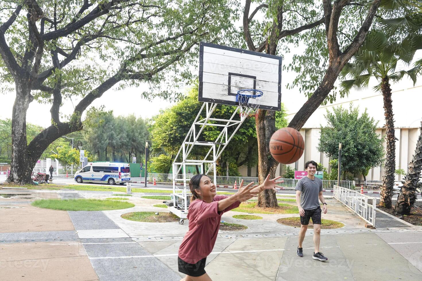 The male and female basketball players practice using the ball in the park court diligently and happily. photo
