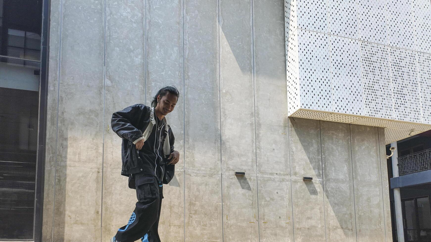 ASian man is dancing in hip hop style at outdoor space. Professional solo dancer is performing in public area. photo