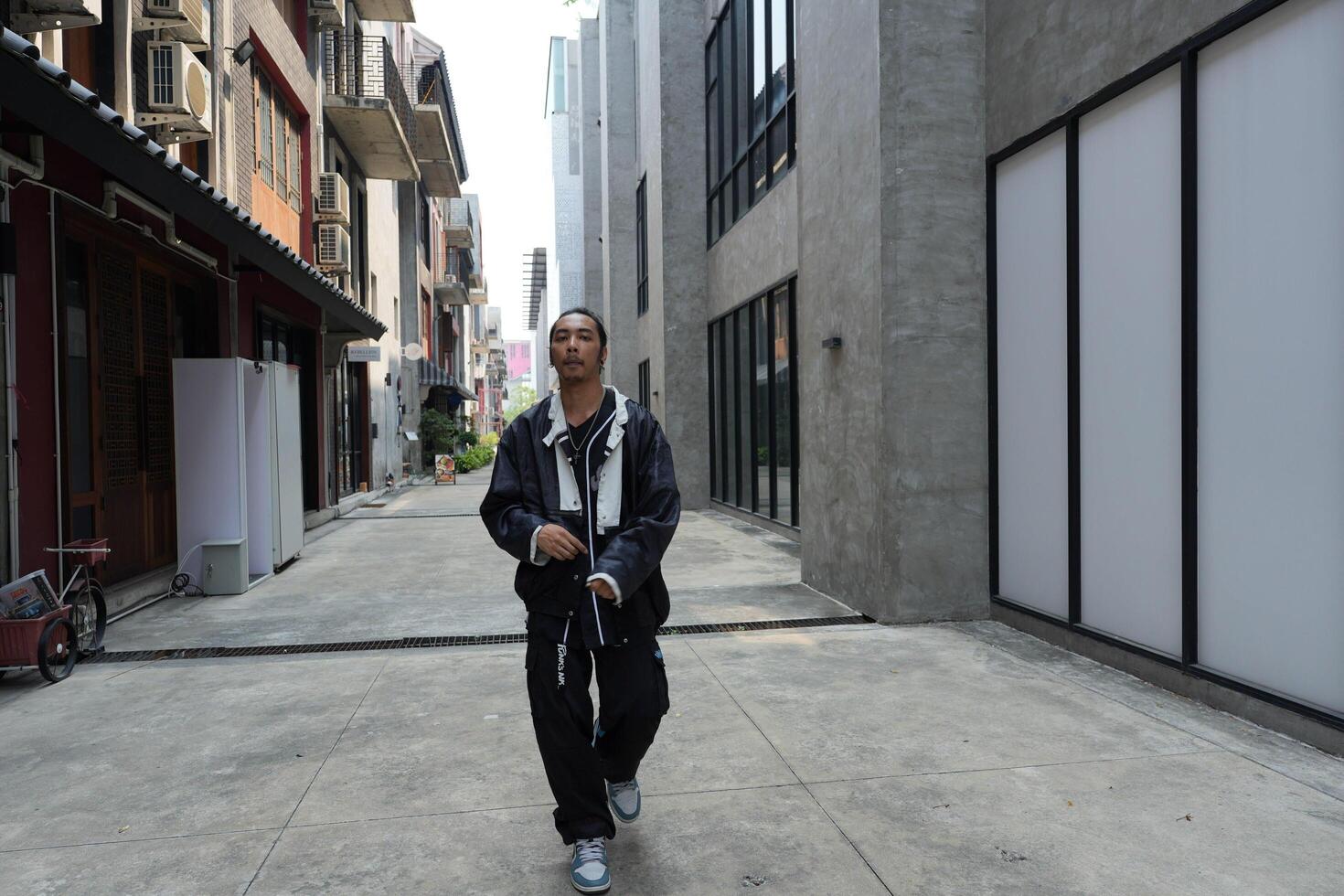 ASian man is dancing in hip hop style at outdoor space. Professional solo dancer is performing in public area. photo