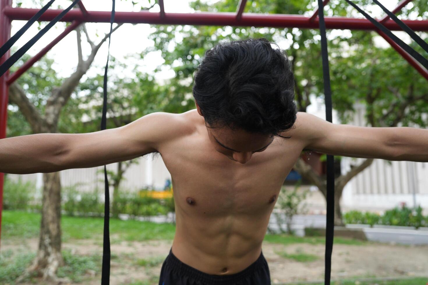Asian man practicing gymnastics, doing gymnastics bar and hoop exercises and stretching, resting for sports. photo
