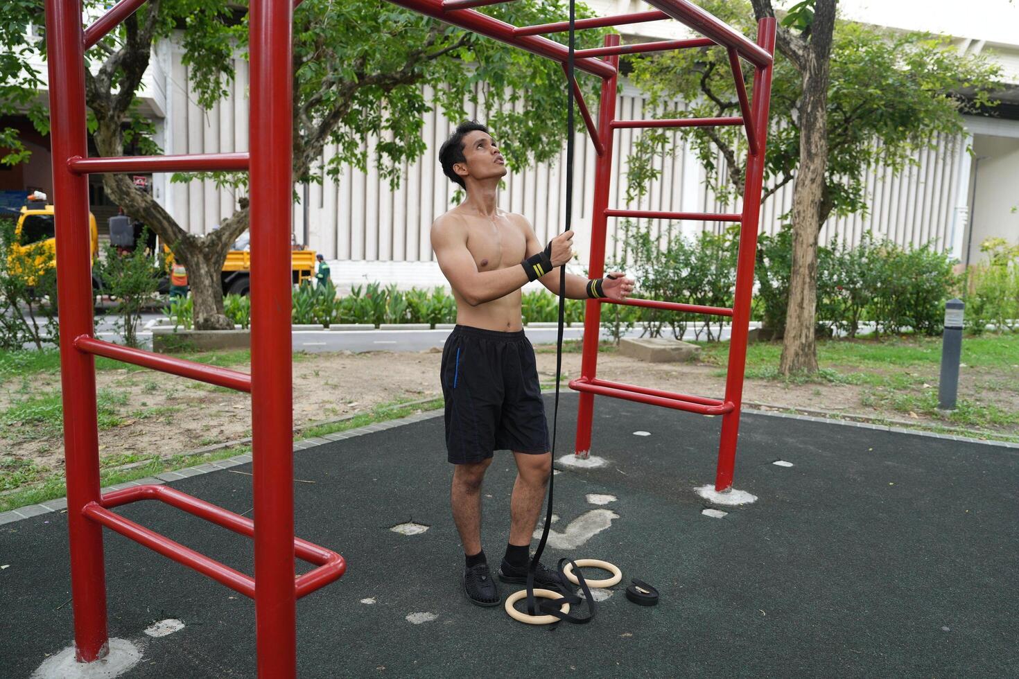 Asian man practicing gymnastics, doing gymnastics bar and hoop exercises and stretching, resting for sports. photo
