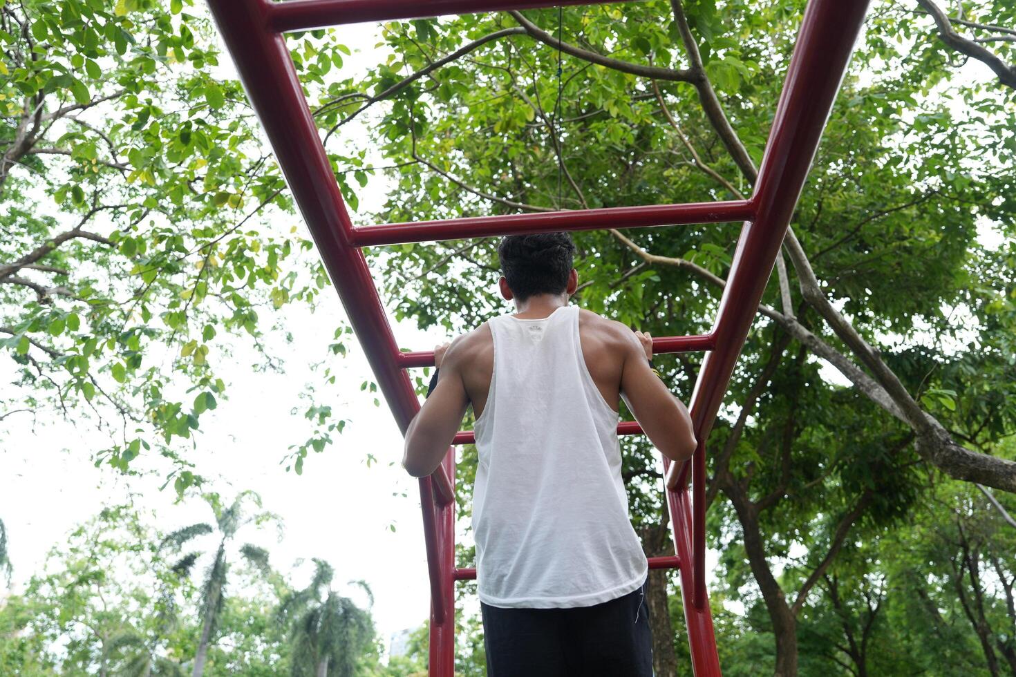Asian man practicing gymnastics, doing gymnastics bar and hoop exercises and stretching, resting for sports. photo