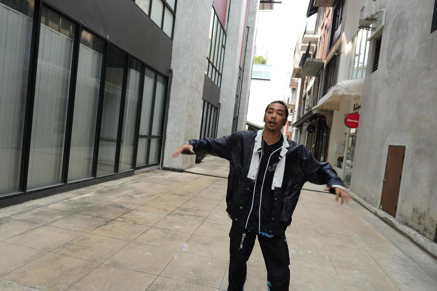 ASian man is dancing in hip hop style at outdoor space. Professional solo dancer is performing in public area. photo