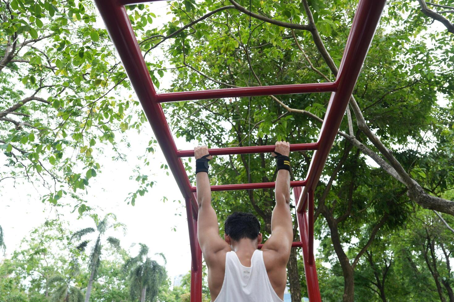 Asian man practicing gymnastics, doing gymnastics bar and hoop exercises and stretching, resting for sports. photo