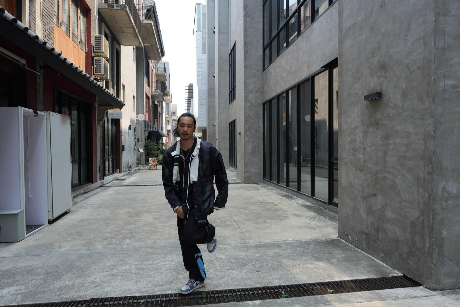 ASian man is dancing in hip hop style at outdoor space. Professional solo dancer is performing in public area. photo
