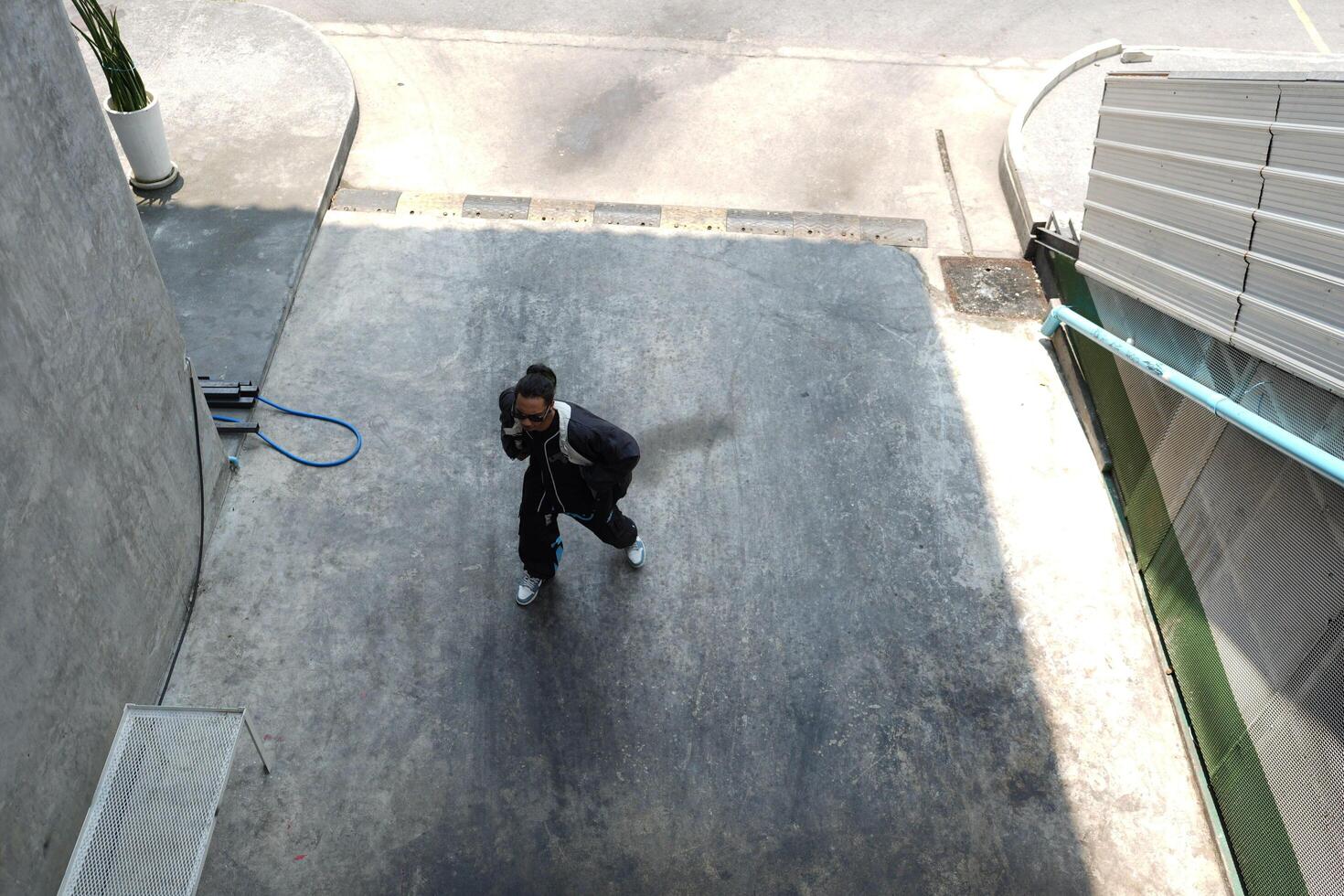 ASian man is dancing in hip hop style at outdoor space. Professional solo dancer is performing in public area. photo
