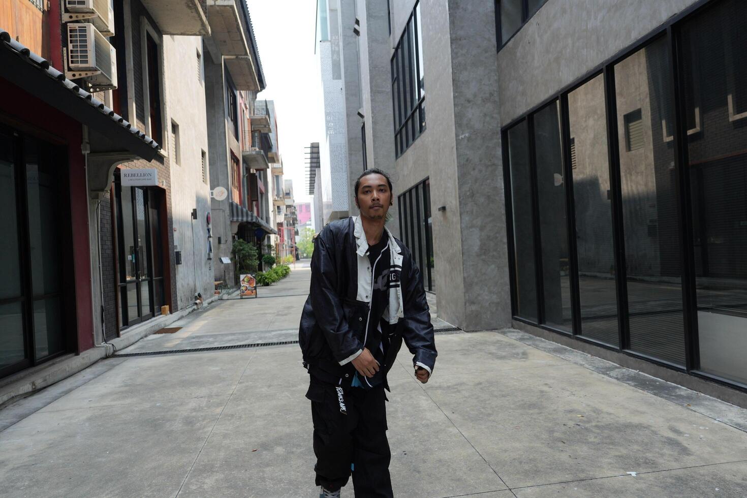 ASian man is dancing in hip hop style at outdoor space. Professional solo dancer is performing in public area. photo