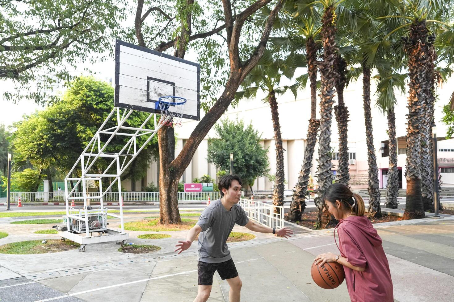 The male and female basketball players practice using the ball in the park court diligently and happily. photo