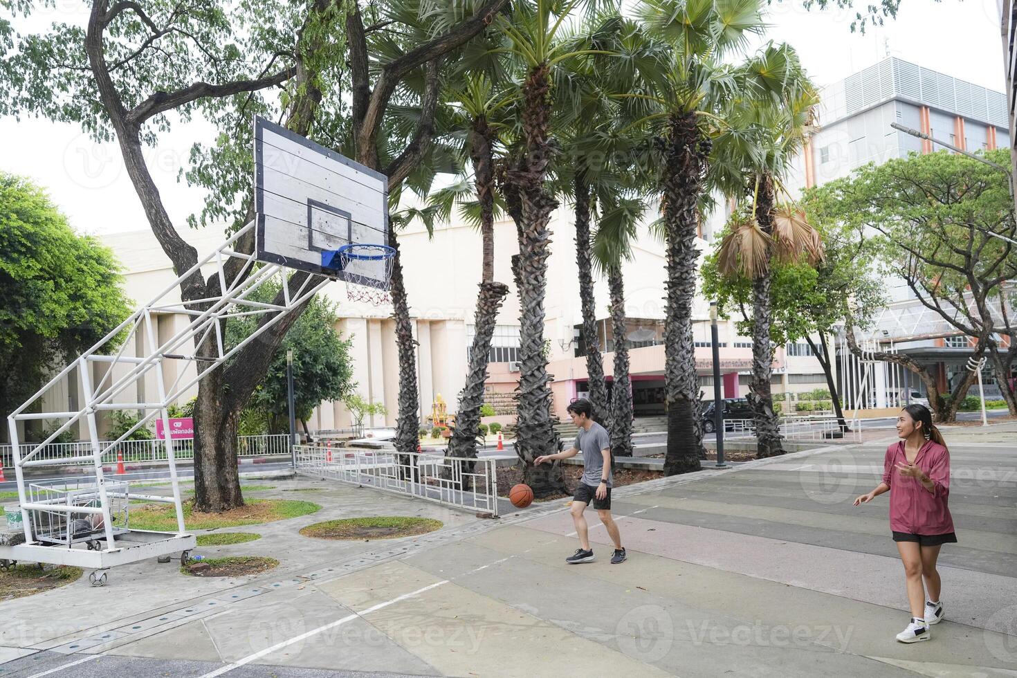 The male and female basketball players practice using the ball in the park court diligently and happily. photo