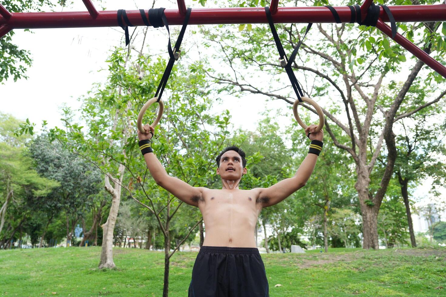 Asian man practicing gymnastics, doing gymnastics bar and hoop exercises and stretching, resting for sports. photo