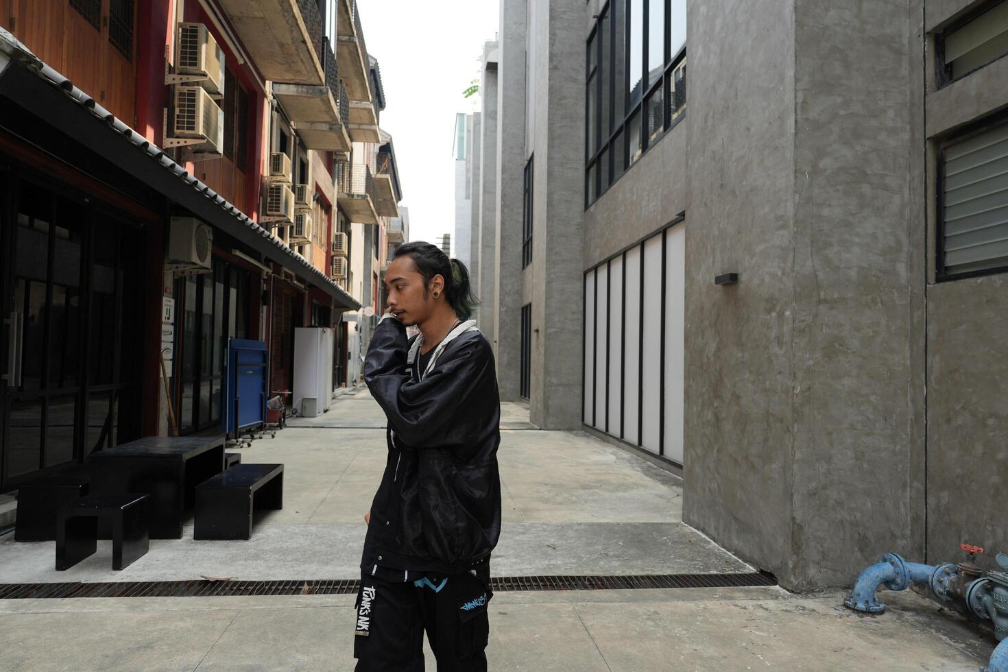 ASian man is dancing in hip hop style at outdoor space. Professional solo dancer is performing in public area. photo