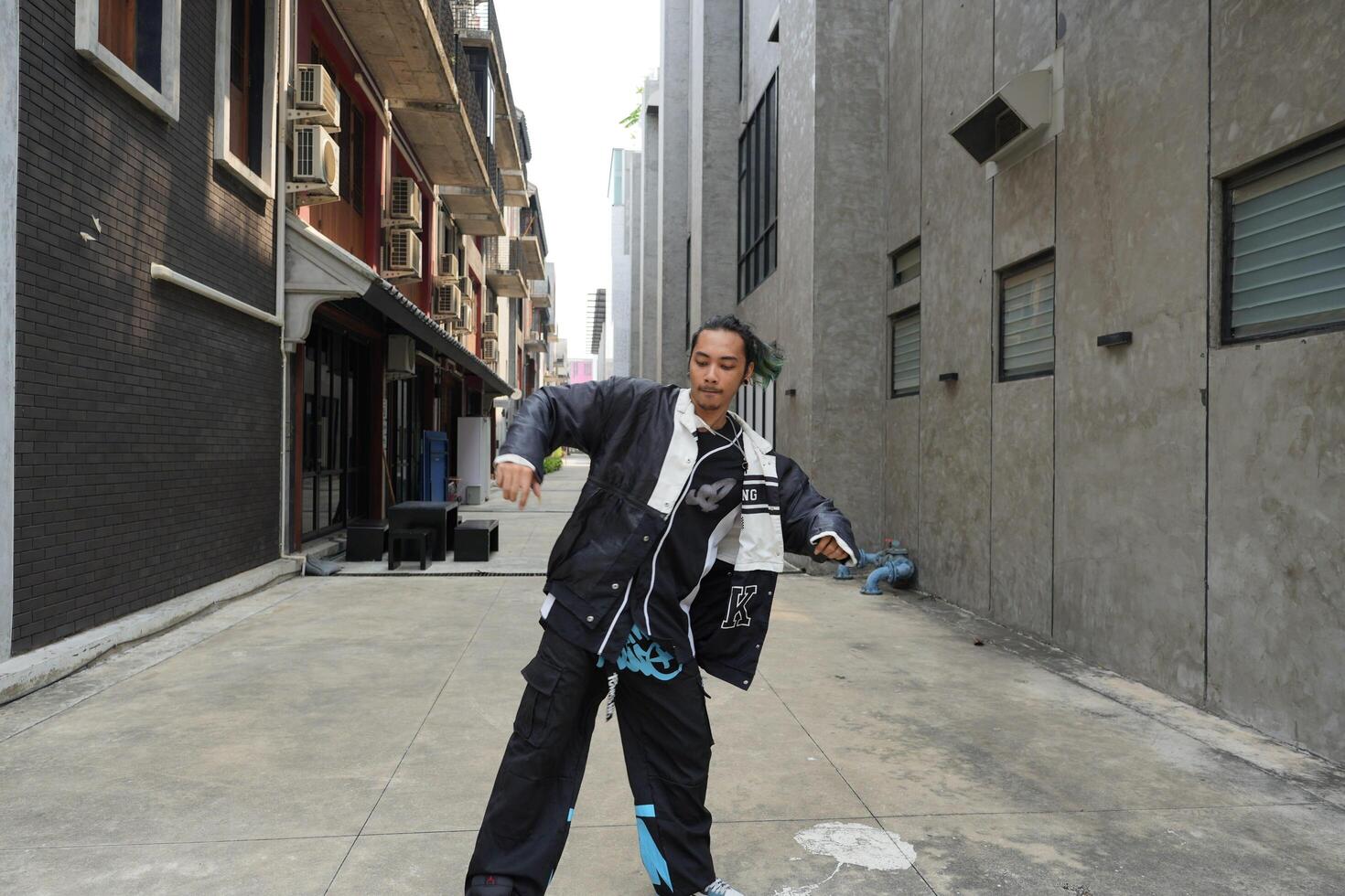 ASian man is dancing in hip hop style at outdoor space. Professional solo dancer is performing in public area. photo