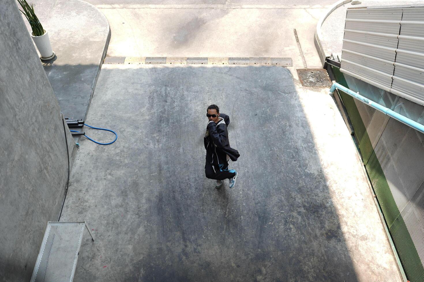 ASian man is dancing in hip hop style at outdoor space. Professional solo dancer is performing in public area. photo