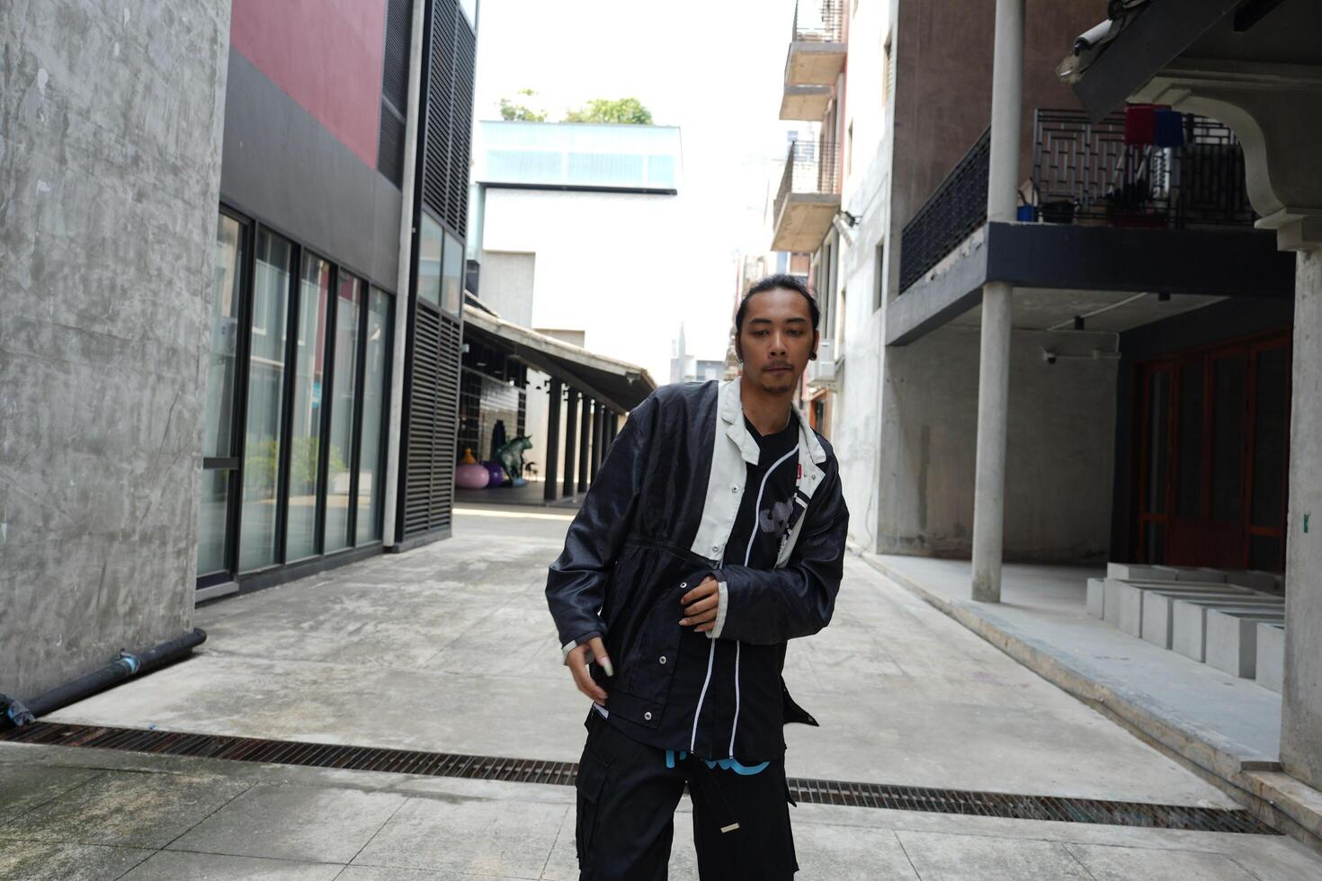 ASian man is dancing in hip hop style at outdoor space. Professional solo dancer is performing in public area. photo