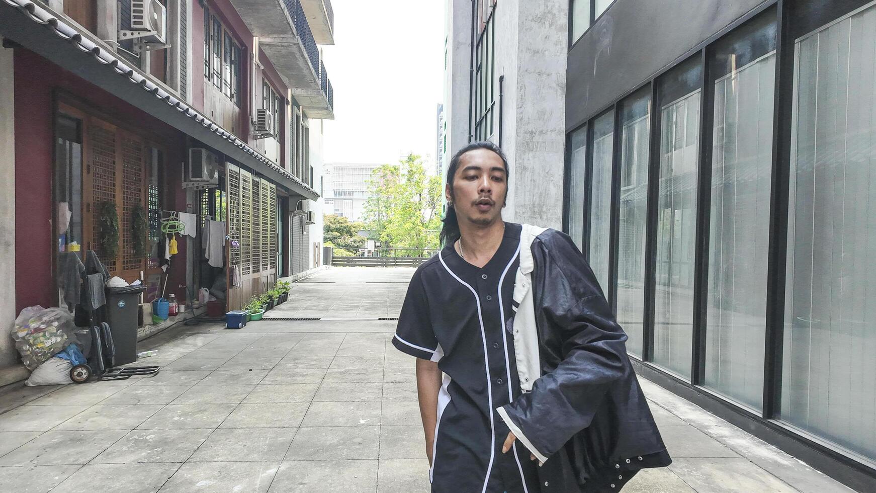 ASian man is dancing in hip hop style at outdoor space. Professional solo dancer is performing in public area. photo