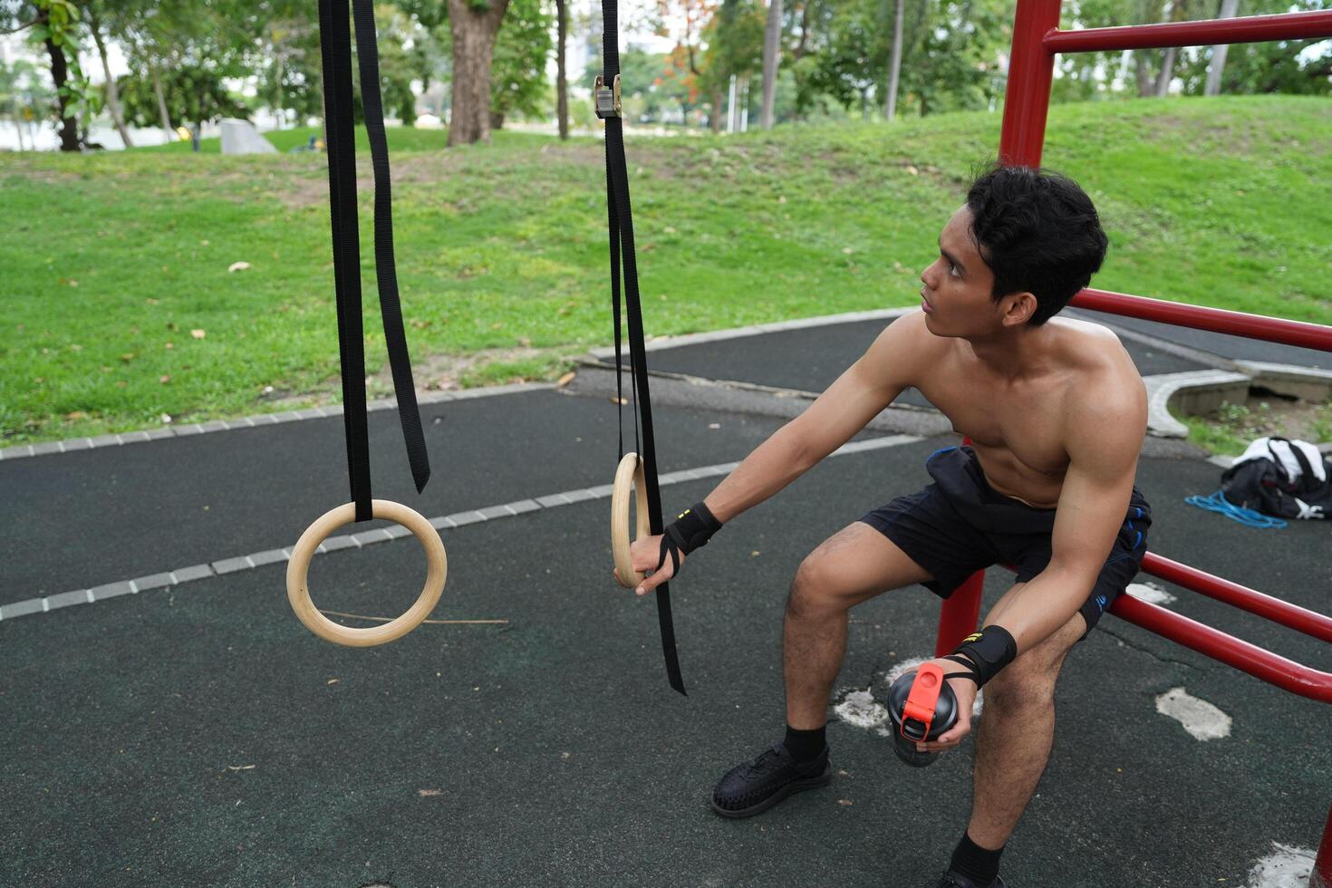 Asian man practicing gymnastics, doing gymnastics bar and hoop exercises and stretching, resting for sports. photo