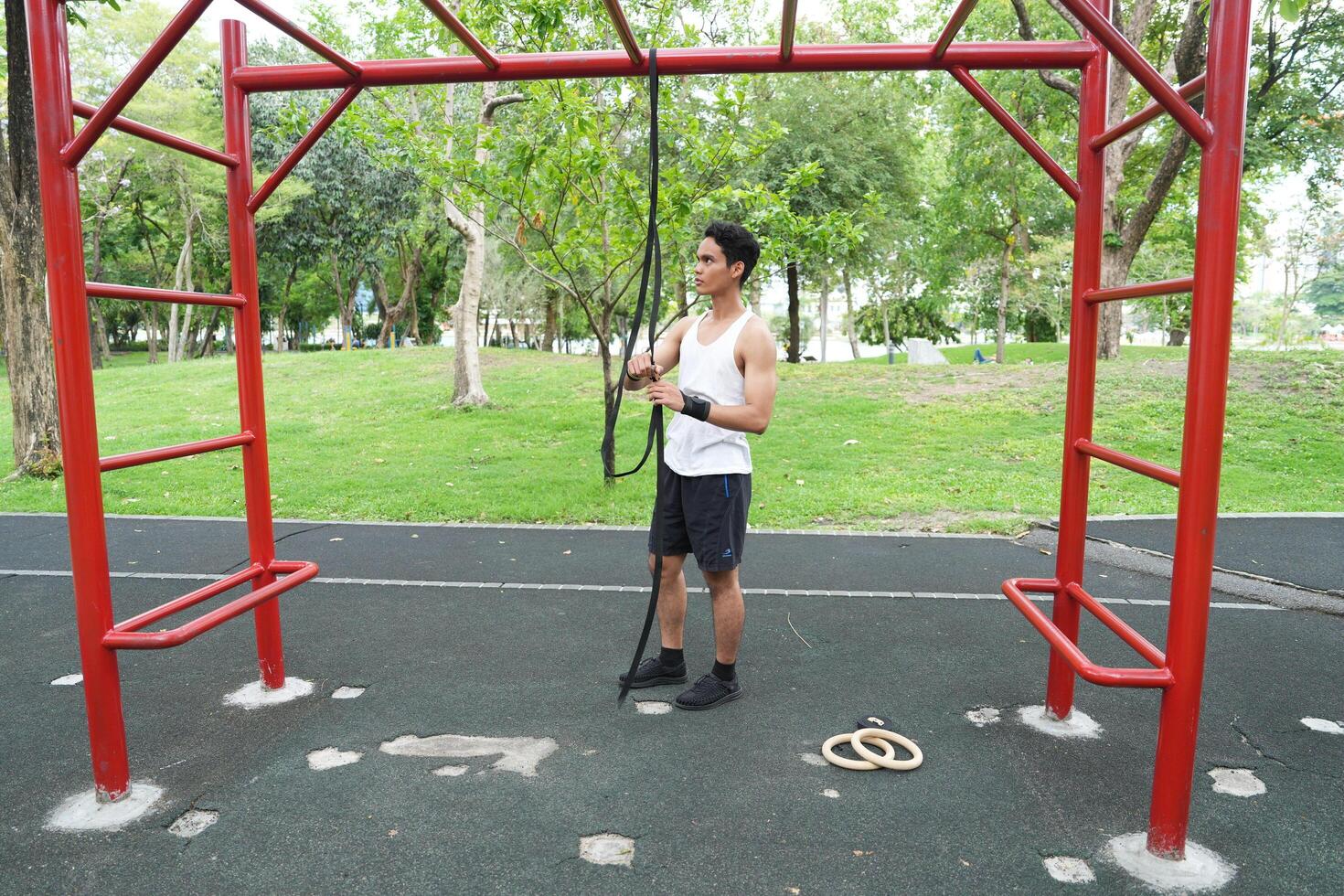 Asian man practicing gymnastics doing gymnastics bar and hoop exercises and stretching and resting for sports. photo