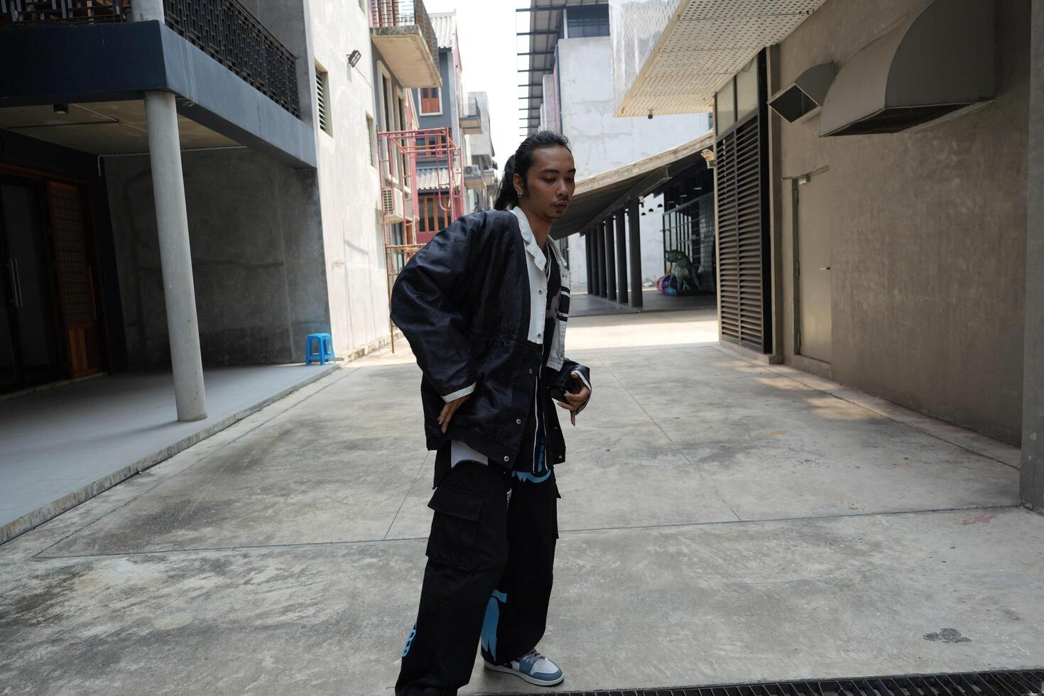 ASian man is dancing in hip hop style at outdoor space. Professional solo dancer is performing in public area. photo