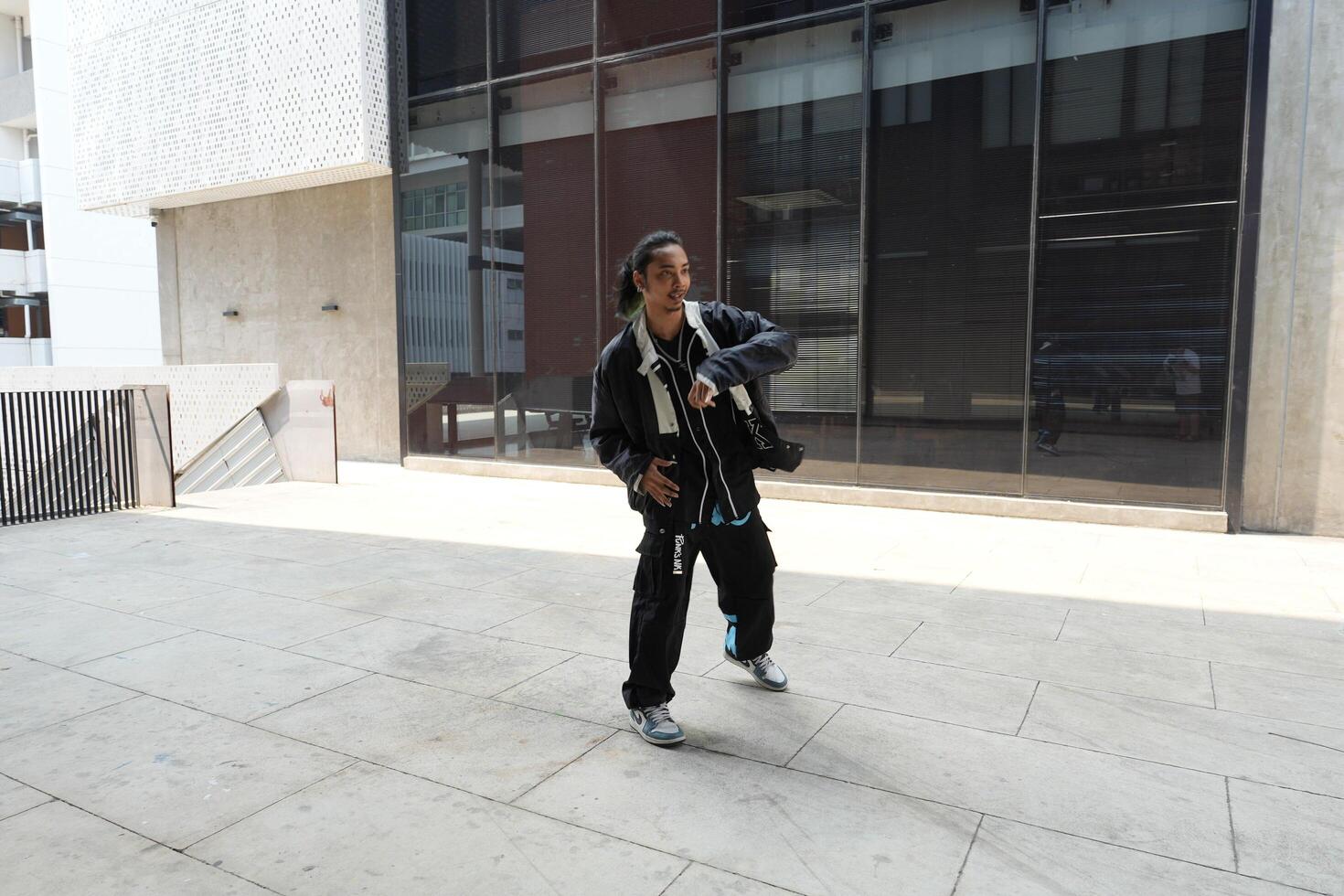ASian man is dancing in hip hop style at outdoor space. Professional solo dancer is performing in public area. photo