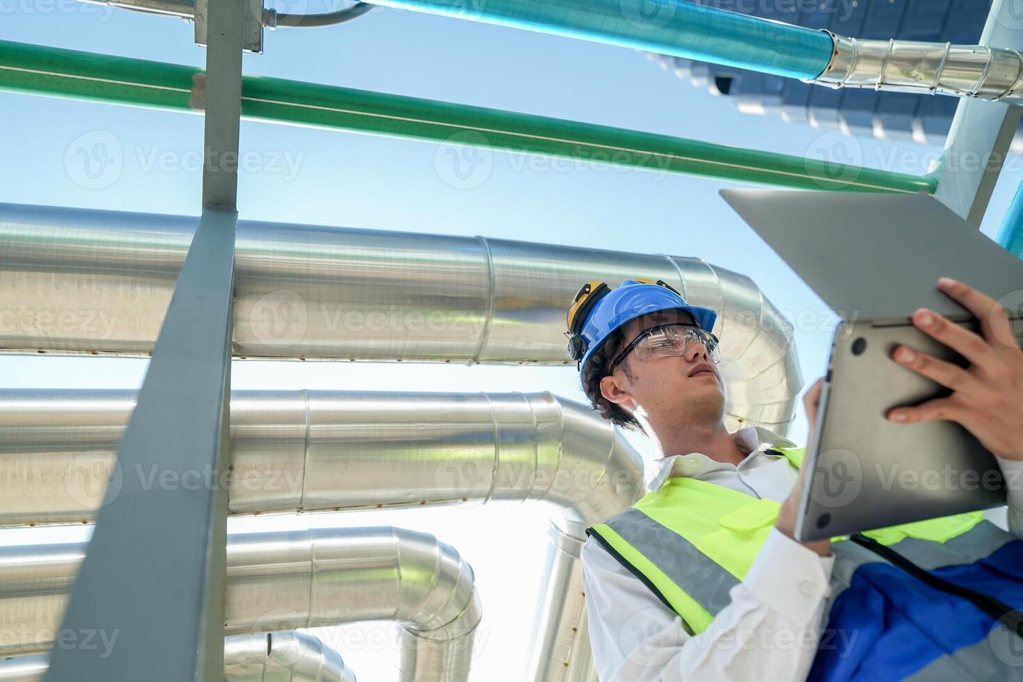 Industrial engineer adjusting pipeline valve with radio communication on construction site. Engineer on urban construction site using radio to coordinate with team on a sunny industrial rooftop. photo