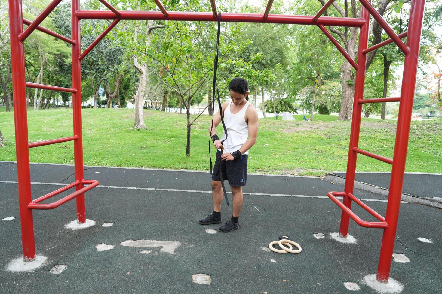 Asian man practicing gymnastics doing gymnastics bar and hoop exercises and stretching and resting for sports. photo