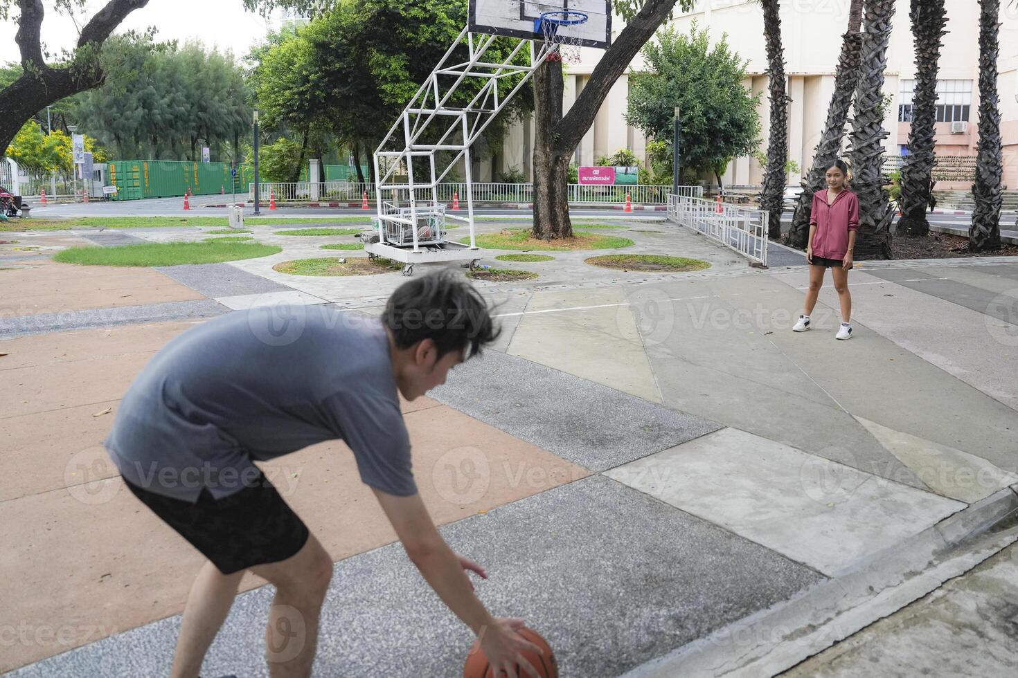 The male and female basketball players practice using the ball in the park court diligently and happily. photo