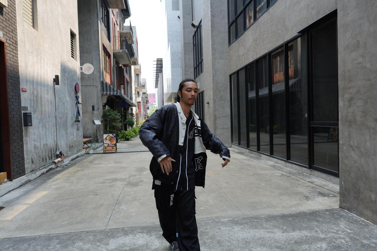ASian man is dancing in hip hop style at outdoor space. Professional solo dancer is performing in public area. photo