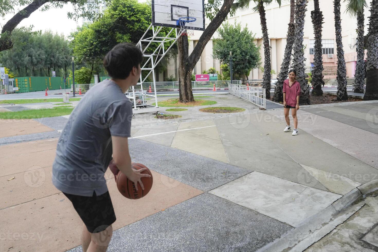 The male and female basketball players practice using the ball in the park court diligently and happily. photo