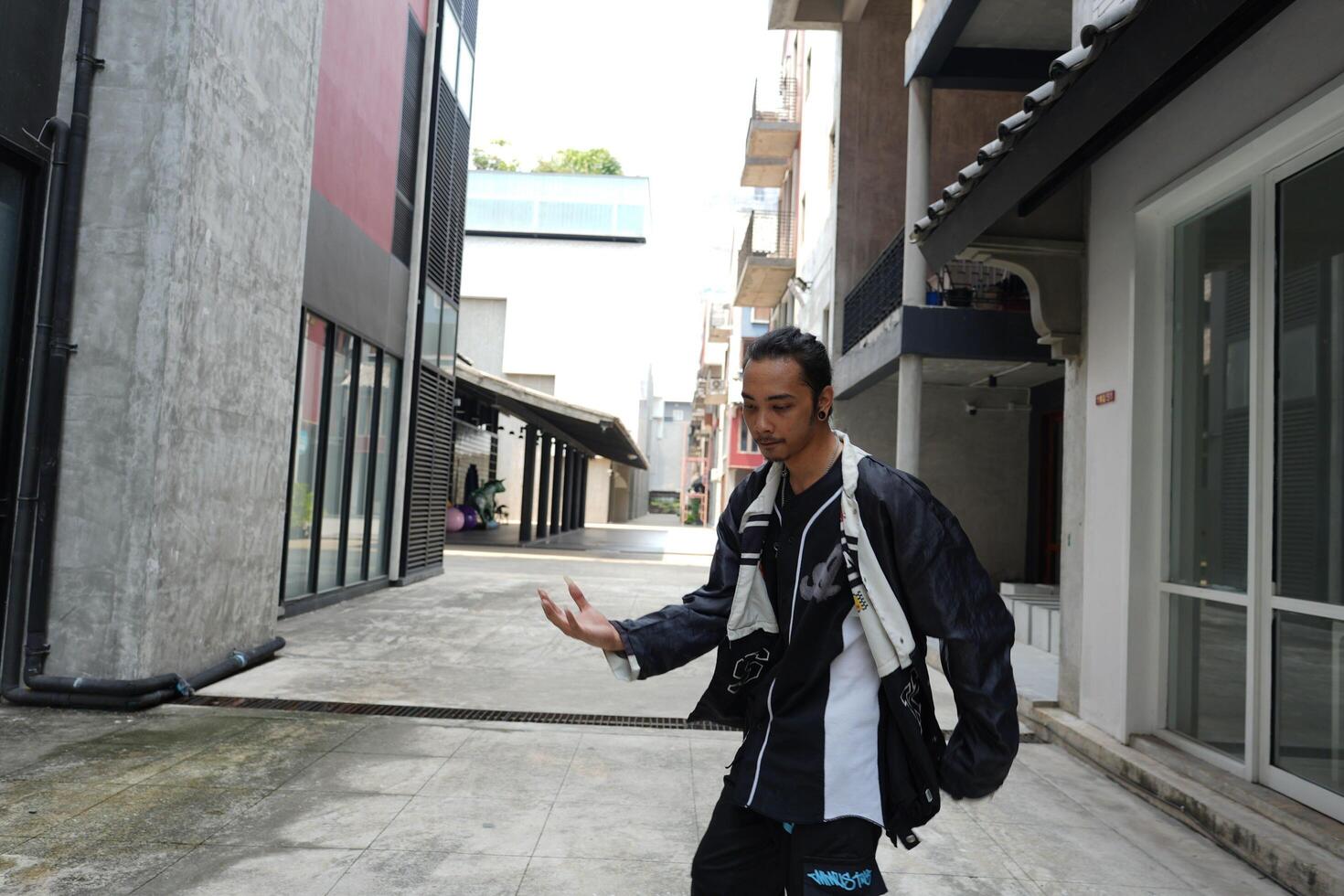 ASian man is dancing in hip hop style at outdoor space. Professional solo dancer is performing in public area. photo