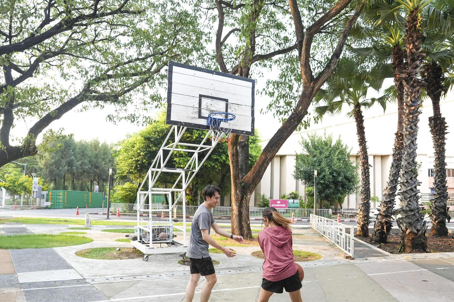 The male and female basketball players practice using the ball in the park court diligently and happily. photo