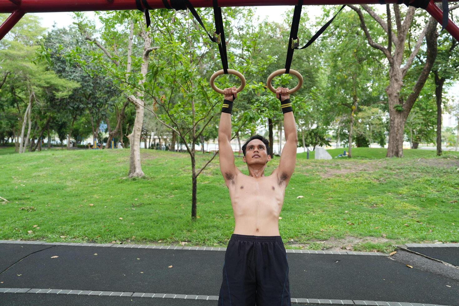 Asian man practicing gymnastics, doing gymnastics bar and hoop exercises and stretching, resting for sports. photo