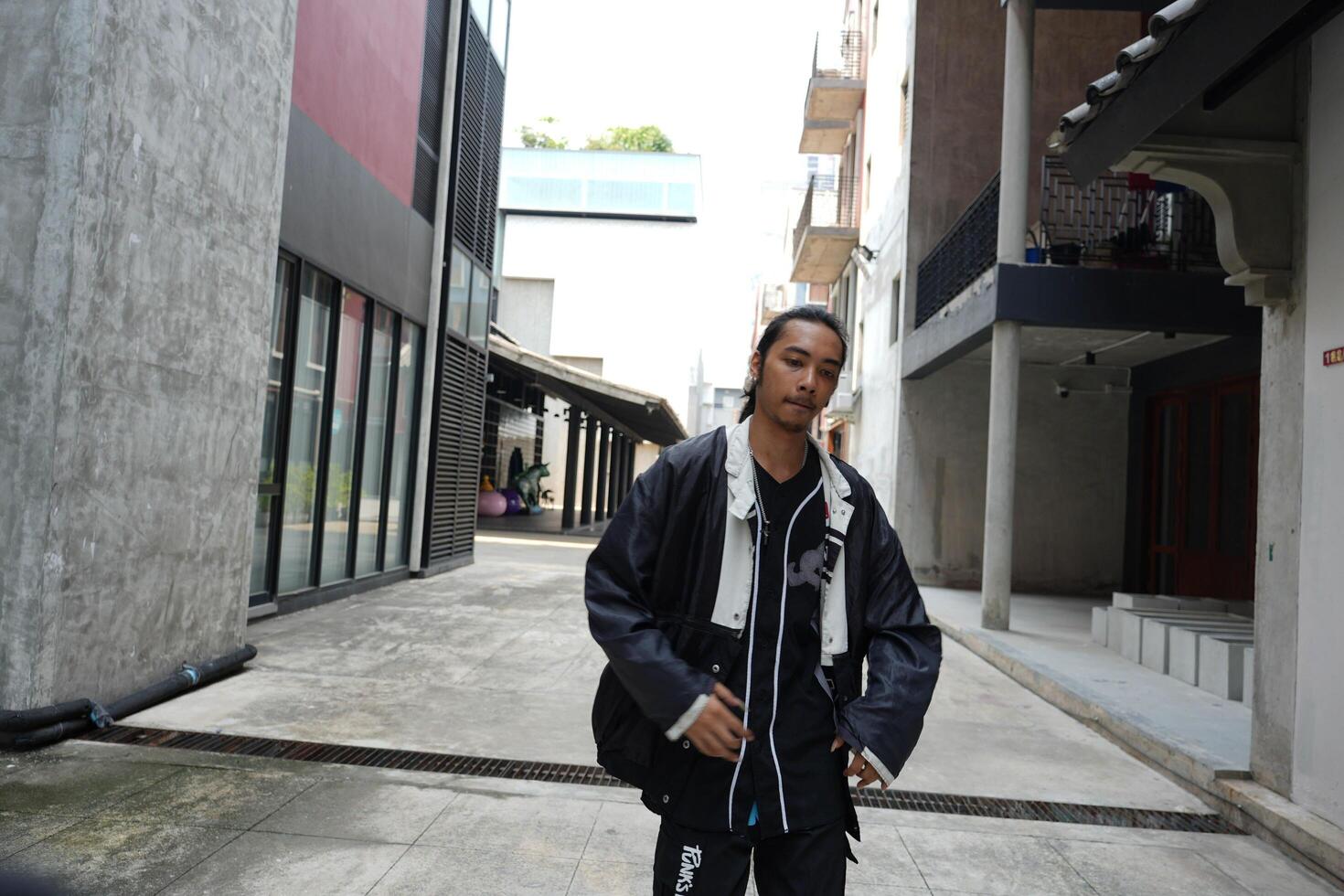 ASian man is dancing in hip hop style at outdoor space. Professional solo dancer is performing in public area. photo