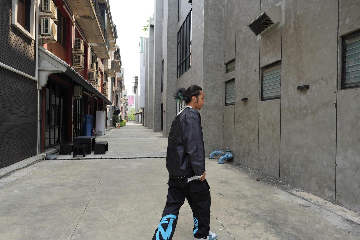 ASian man is dancing in hip hop style at outdoor space. Professional solo dancer is performing in public area. photo