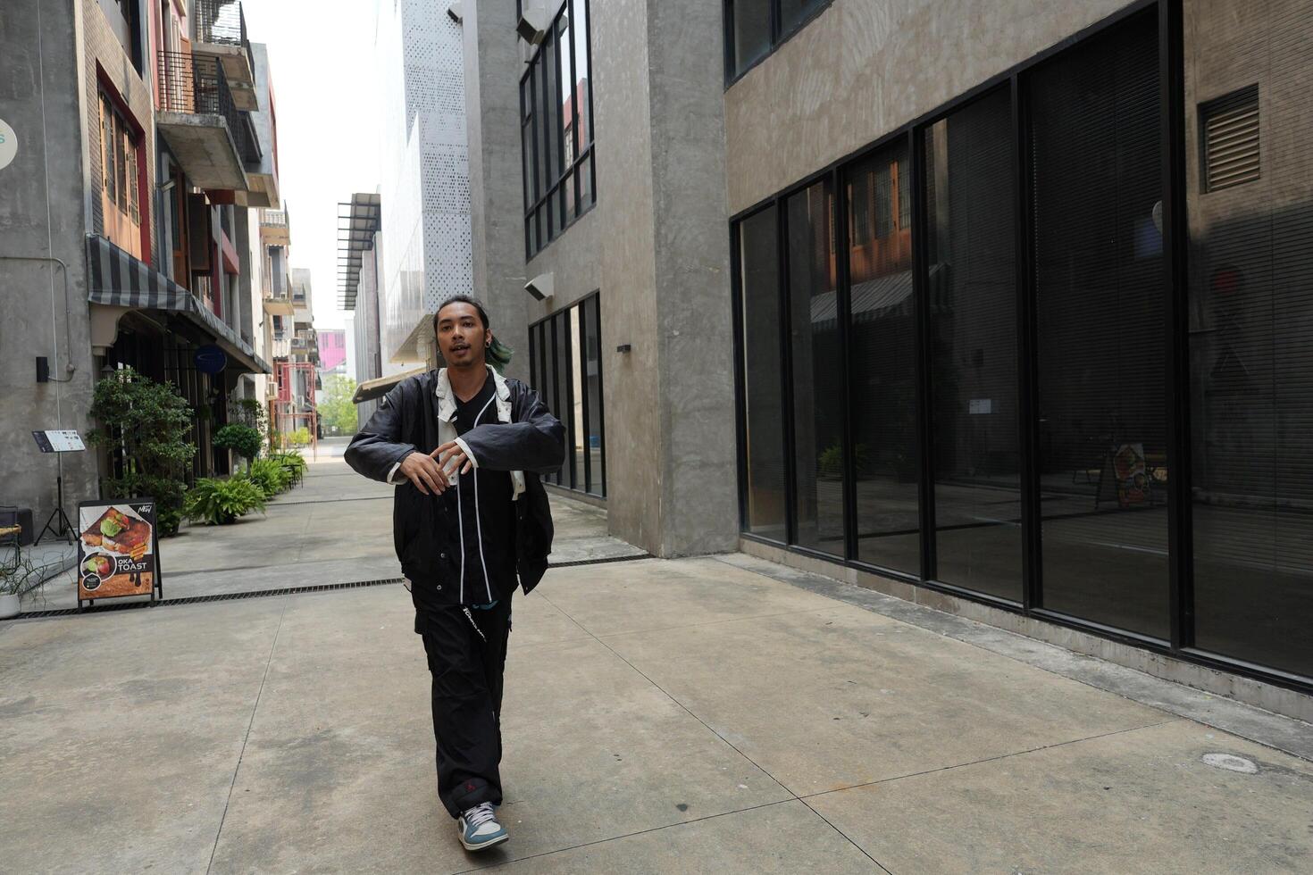 ASian man is dancing in hip hop style at outdoor space. Professional solo dancer is performing in public area. photo