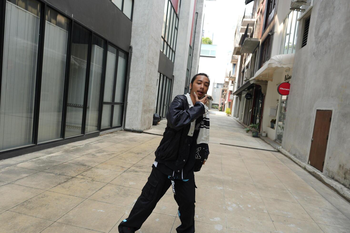 ASian man is dancing in hip hop style at outdoor space. Professional solo dancer is performing in public area. photo