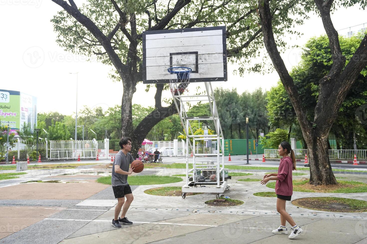 The male and female basketball players practice using the ball in the park court diligently and happily. photo