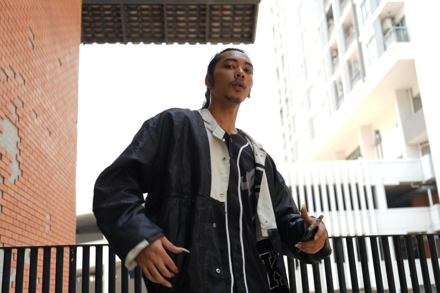 ASian man is dancing in hip hop style at outdoor space. Professional solo dancer is performing in public area. photo