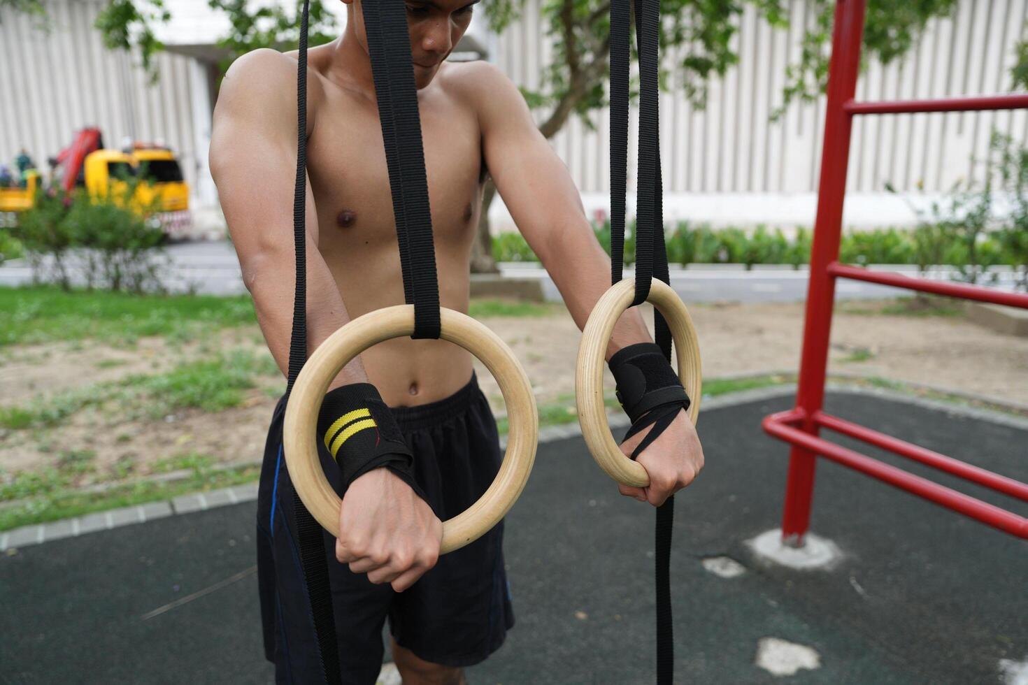 Asian man practicing gymnastics, doing gymnastics bar and hoop exercises and stretching, resting for sports. photo