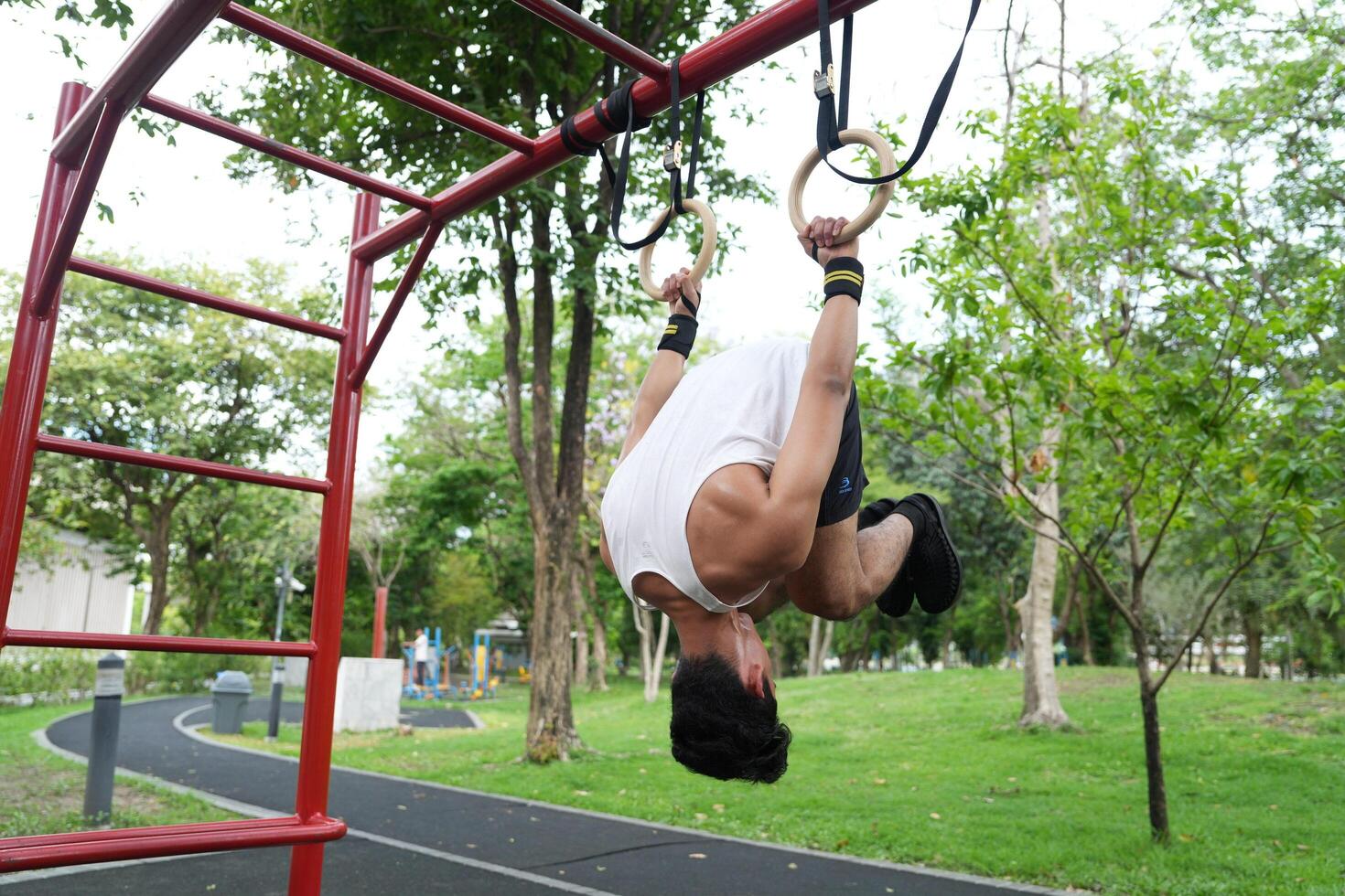 Asian man practicing gymnastics, doing gymnastics bar and hoop exercises and stretching, resting for sports. photo