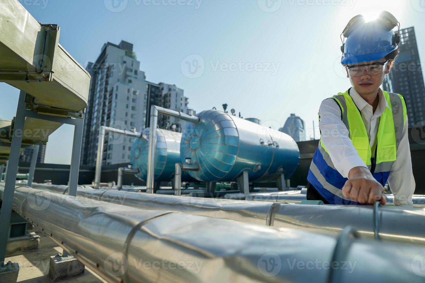 Urban rooftop scene showing a young engineer with a radio, inspecting and adjusting equipment in a sunny city environment. Safety and precision at work. photo