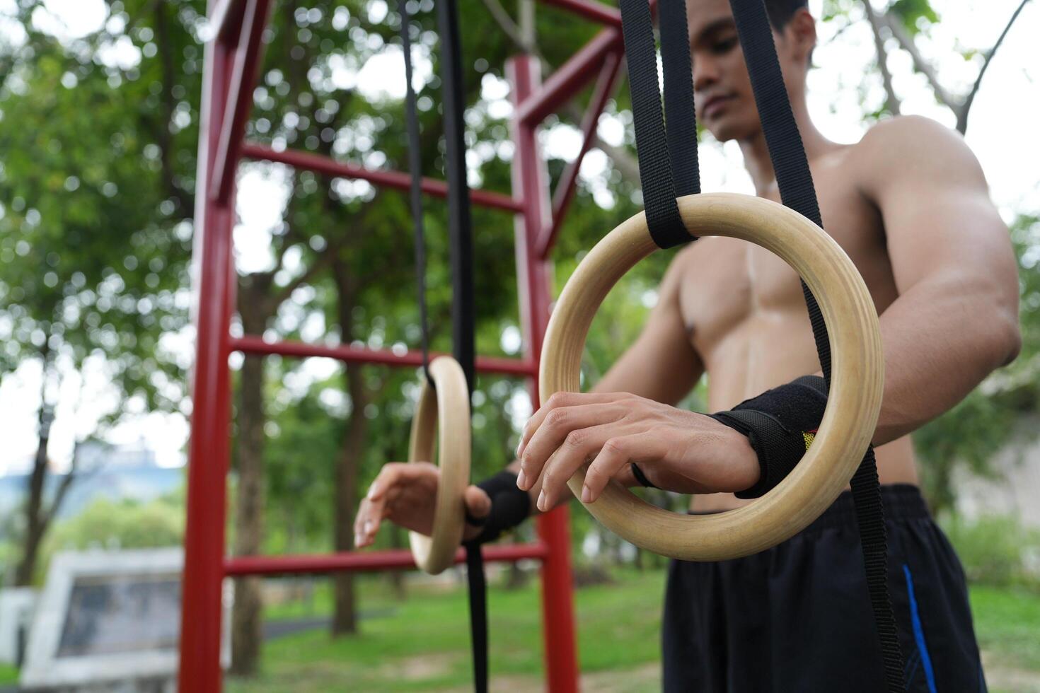 Asian man practicing gymnastics, doing gymnastics bar and hoop exercises and stretching, resting for sports. photo