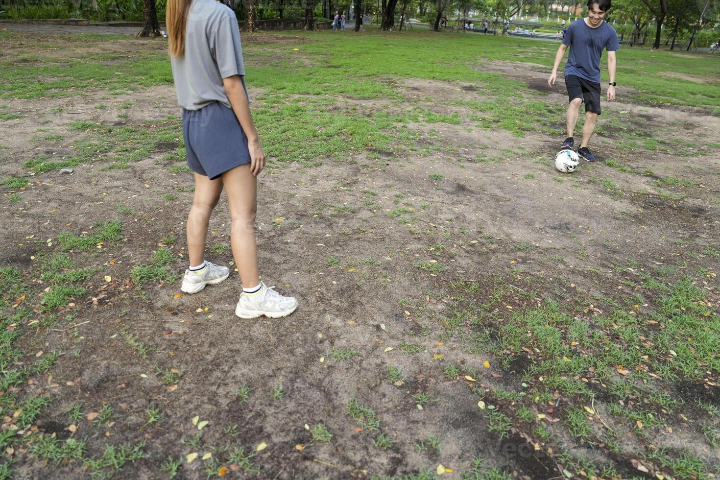 Asian man and woman are kicking and warming up before playing in soccer at outdoor park. photo