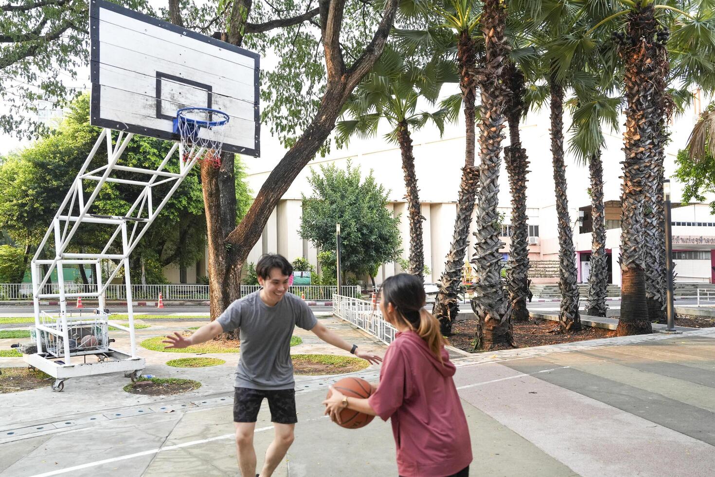 The male and female basketball players practice using the ball in the park court diligently and happily. photo