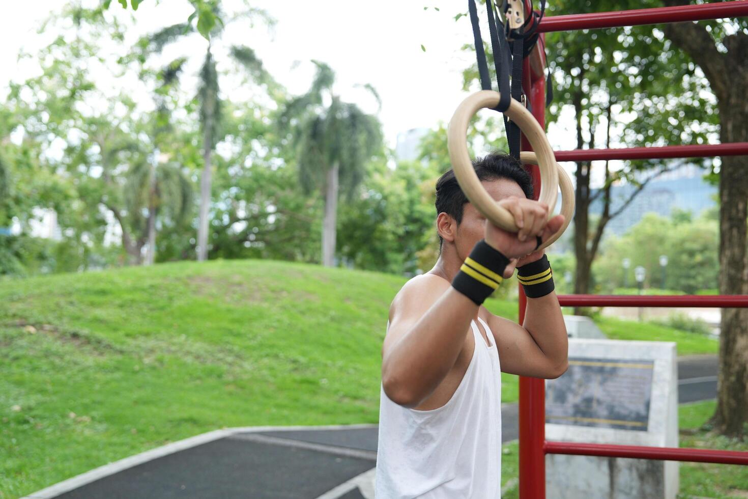 Asian man practicing gymnastics, doing gymnastics bar and hoop exercises and stretching, resting for sports. photo