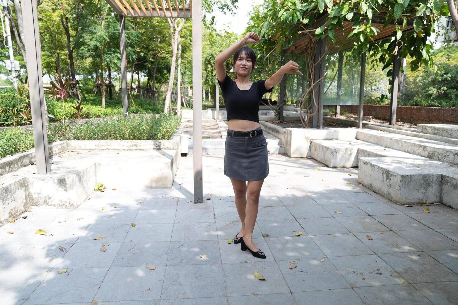 Asian woman dancing in the middle of a park photo