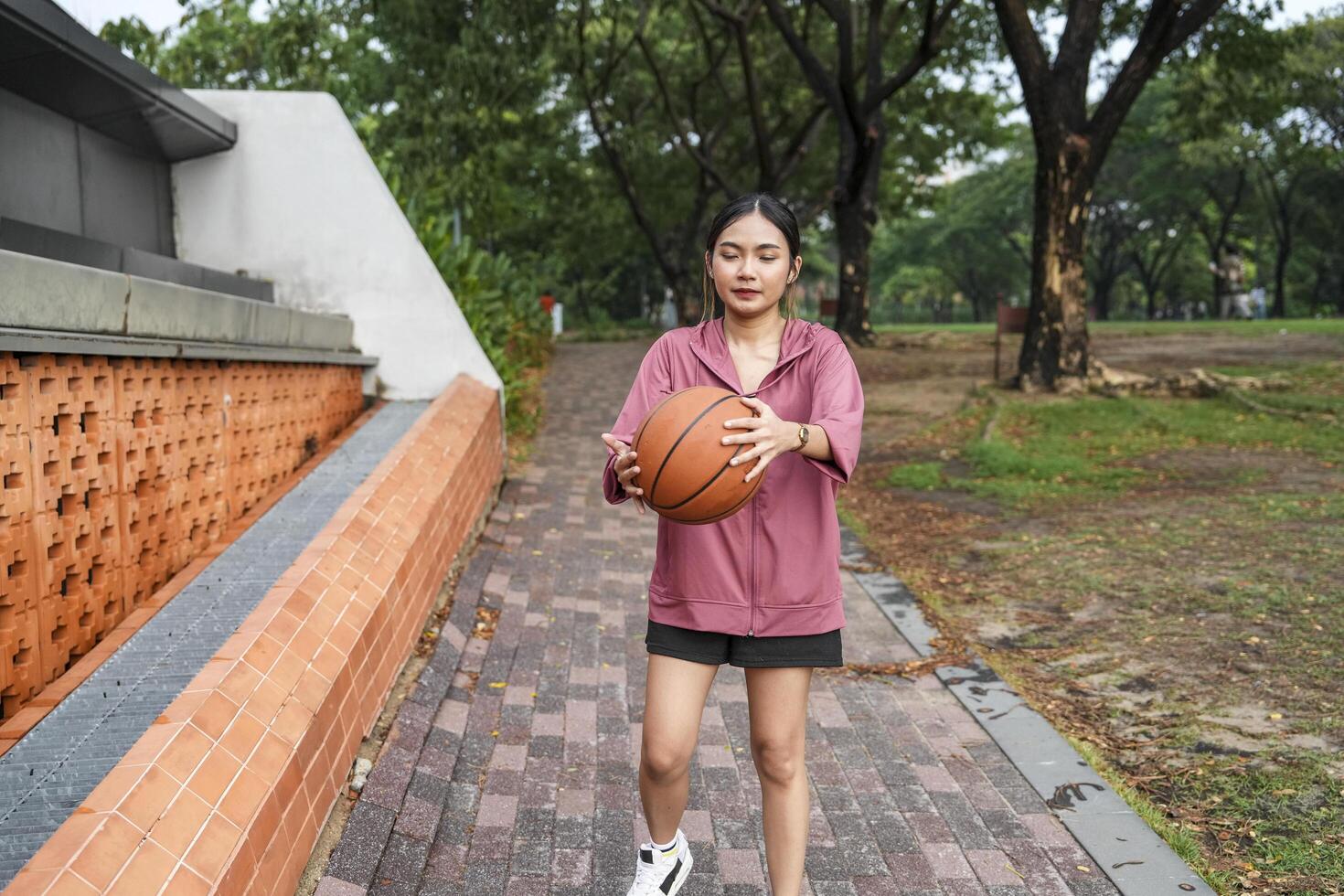 A woman plays basketball alone in a public section. photo