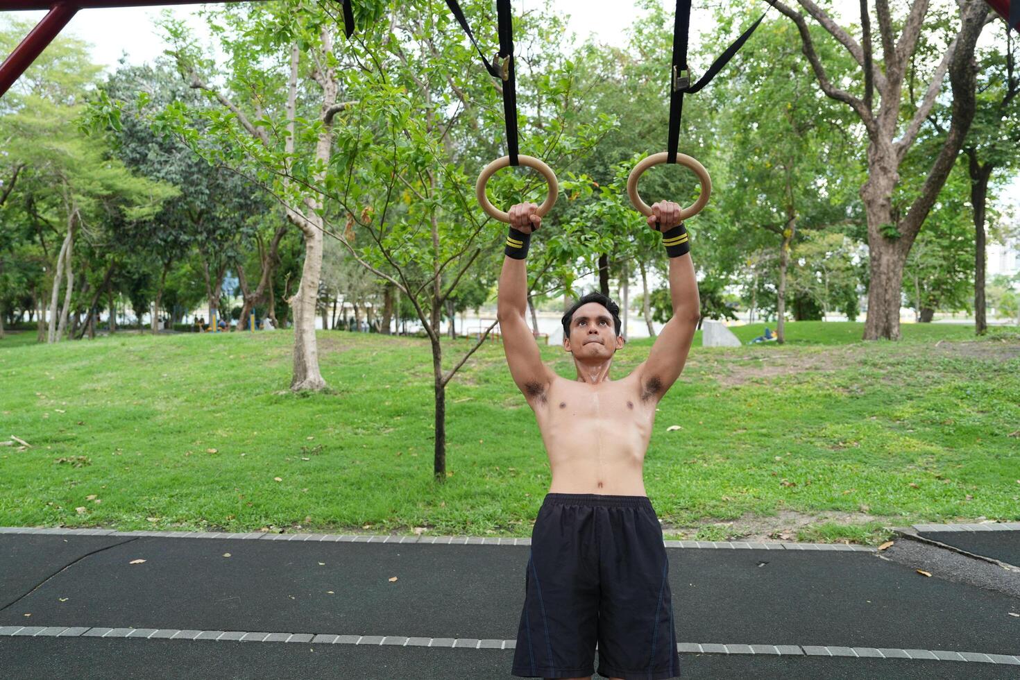 Asian man practicing gymnastics, doing gymnastics bar and hoop exercises and stretching, resting for sports. photo